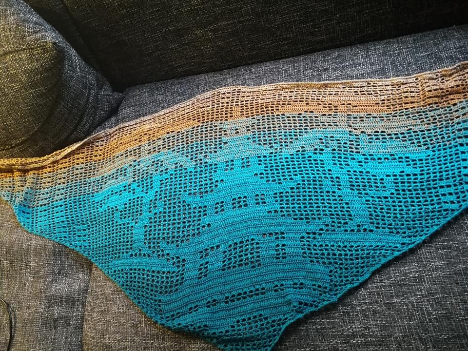 Dreieckiges gehäkeltes Tuch in Braun und Türkis mit Filetmuster und Fischmotiven auf Sofa