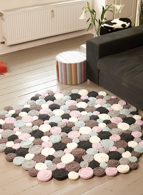 Runder Teppich aus dicht angeordneten gestrickten Ronden in Pastell- und Naturtönen