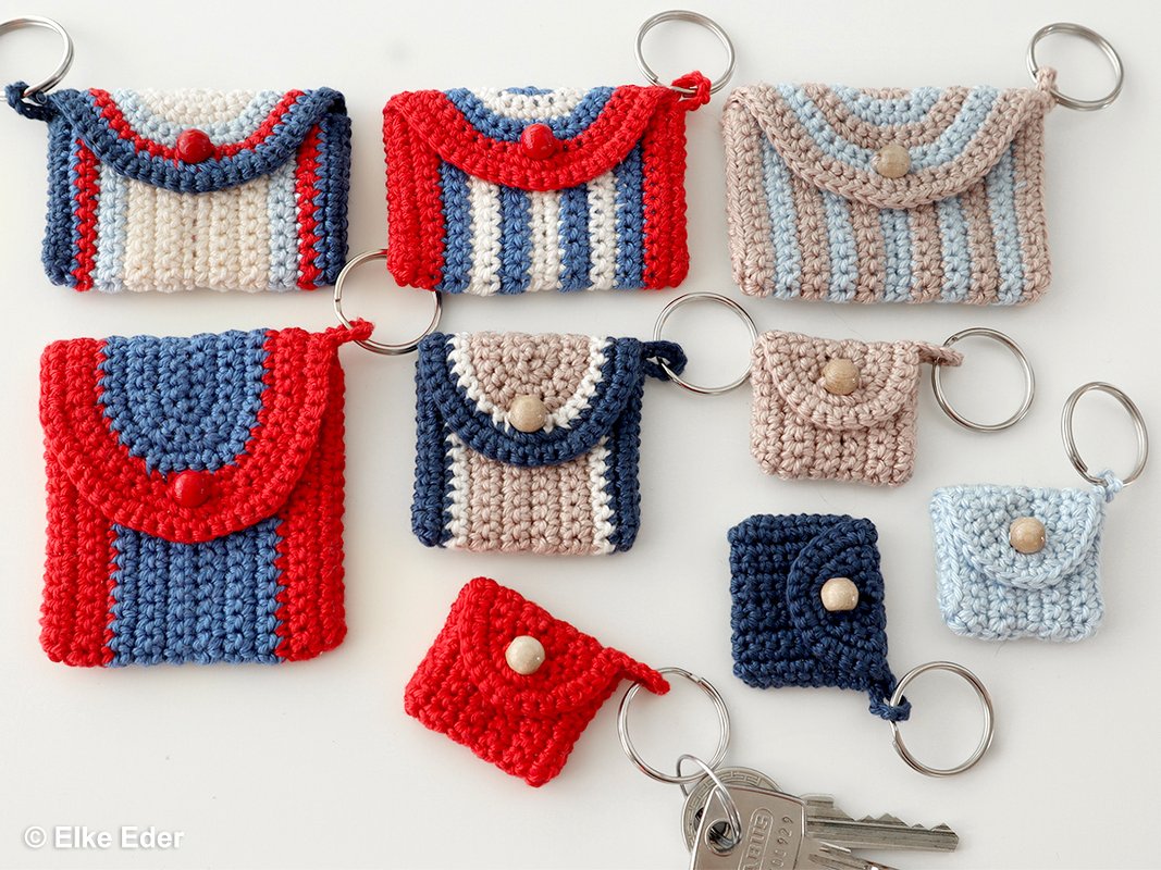 Assortment of small crocheted keychain pouches in red, blue and beige with buttons and metal rings