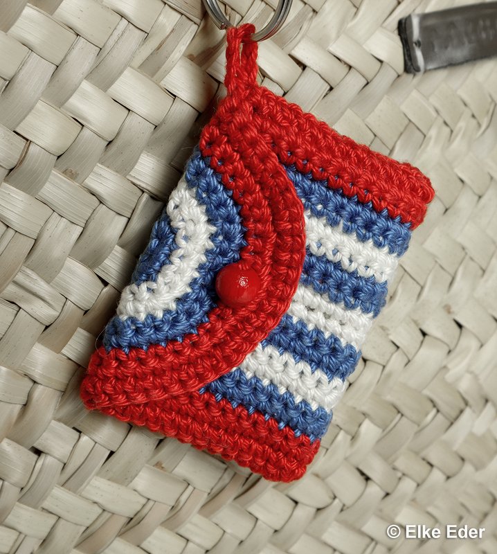 Crocheted keychain pouch with red, white and blue stripes and a red button flap.