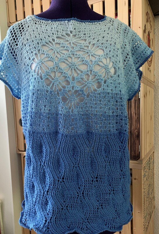 Gehäkeltes blaues Damen-Shirt mit Farbverlauf, Blüten- und Wellenmuster auf Schneiderpuppe