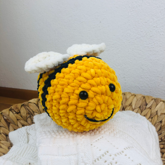 Gehäkelte gelb-schwarz gestreifte Biene mit weißen Flügeln in einem Korb