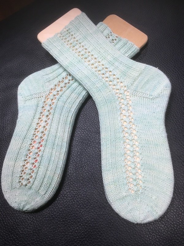 Handgestrickte mintgrüne Damensocken mit Ajour-Lochmuster auf Sockenspannern.