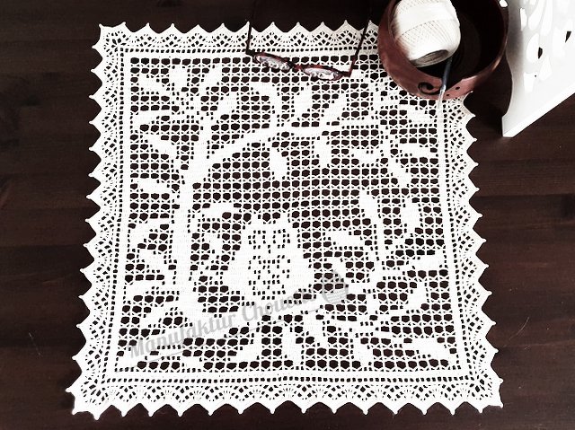 Weißes gehäkeltes Deckchen mit Baummotiv auf dunklem Holztisch