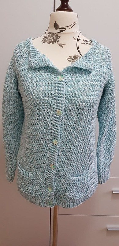 Gehäkelte hellblaue Damenjacke mit Umlegekragen, Knopfleiste und Taschen auf Schneiderpuppe