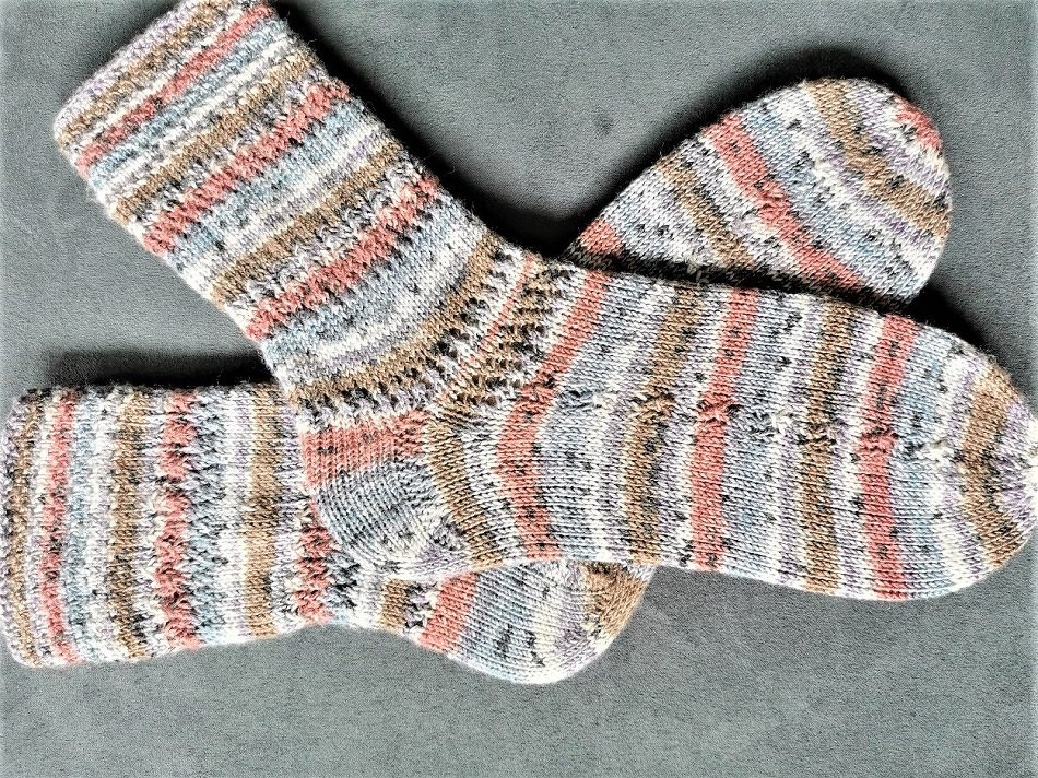 Gestricktes Paar Damensocken mit Pastellstreifen auf grauem Hintergrund