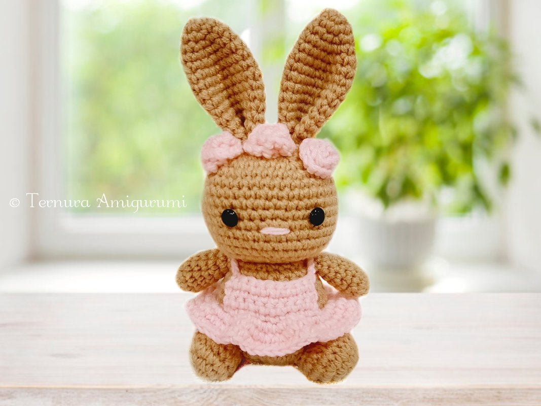 Braunes handgehäkeltes Amigurumi-Häschen mit rosa Kleid und Blüten