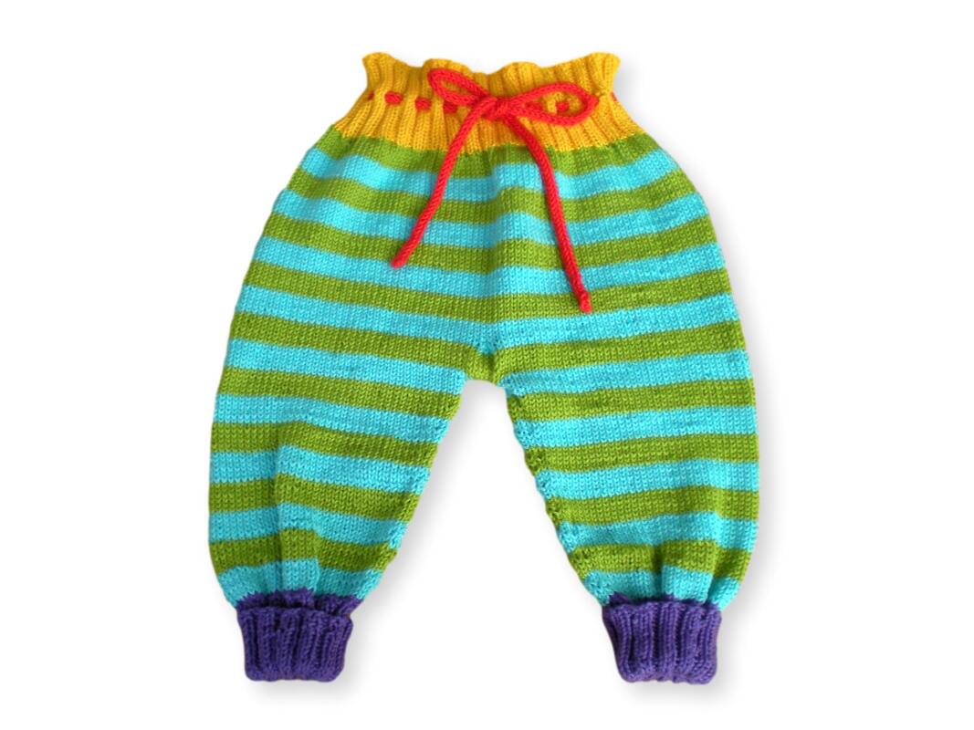 Knitted baby pants with green and turquoise stripes, yellow ruffled waistband, red drawstring, and purple ribbed ankle cuffs.