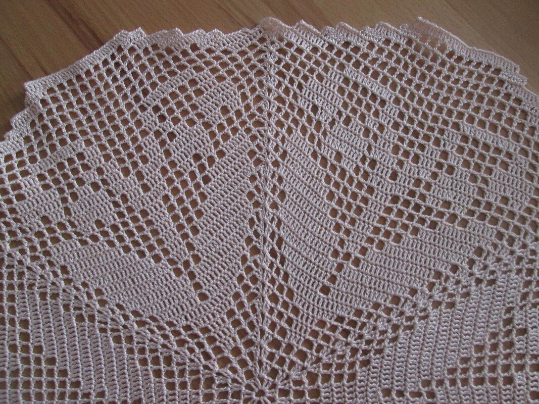Gehäkeltes Deckchen in hellem Beige mit Gitter- und Rautenmuster auf Holzuntergrund