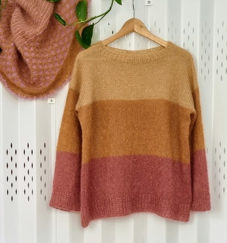 Gestreifter Pullover mit Rundhals in Creme, Karamell und Altrosa an einem Holzbügel
