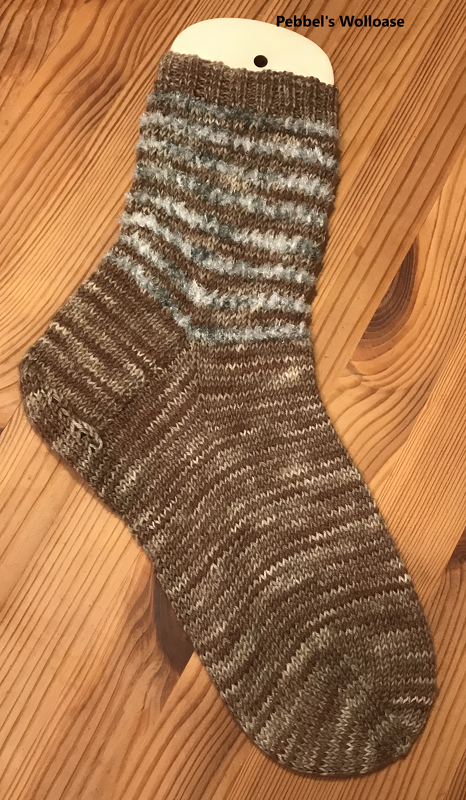 Gestrickte Damensocke in Braun- und Hellblautönen auf Holzuntergrund