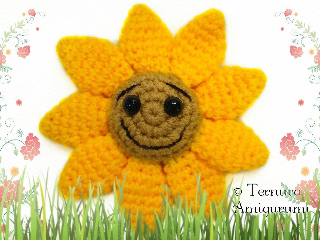 Crocheted sunflower amigurumi with yellow petals and a smiling brown center