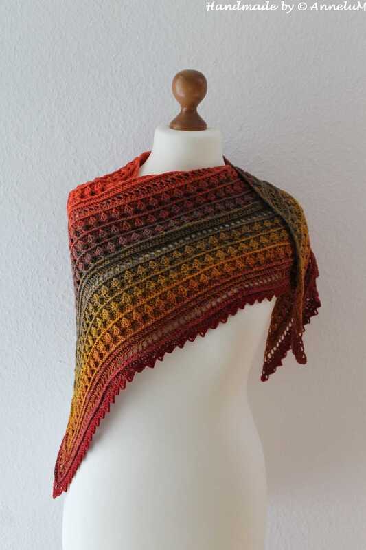 Crocheted triangle shawl on a mannequin with rust, gold and olive gradient, textured stitch rows and a scalloped border.