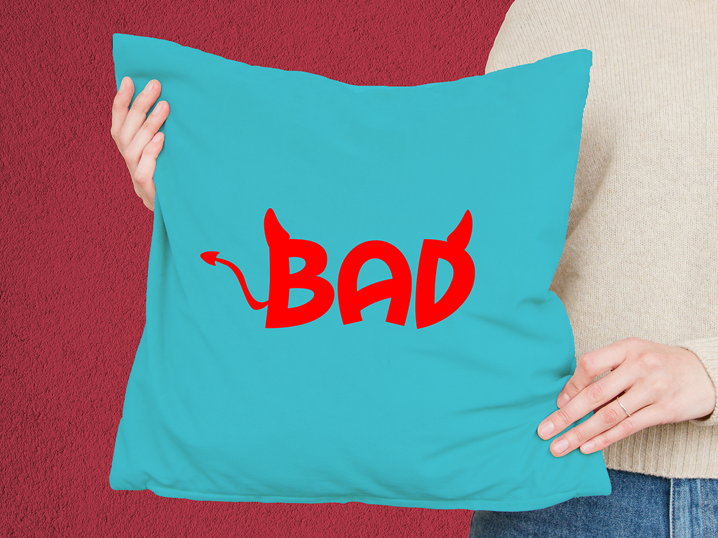 Türkisfarbenes Kissen mit rotem 'BAD'-Schriftzug im Teufelsstil