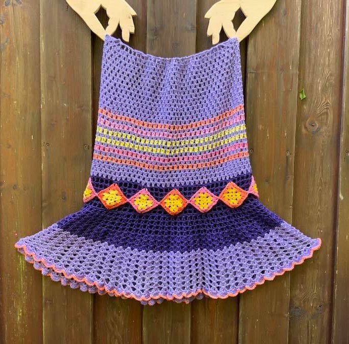 Lila Häkelkleid mit bunten Streifen, gelber Rautenborte und Wellenkante