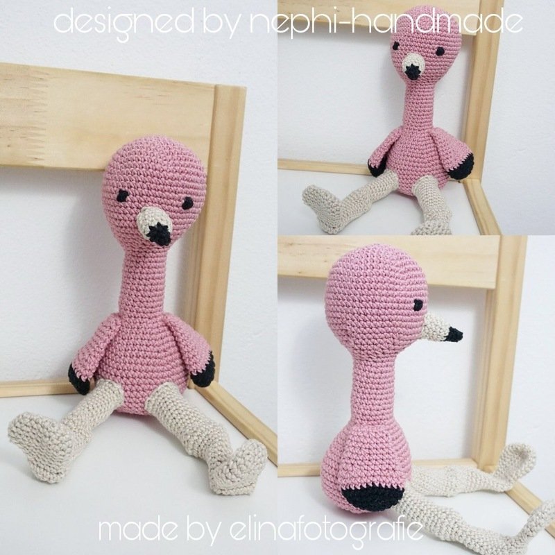 Rosa gehäkelter Flamingo-Amigurumi, sitzend, mit beigen Beinen und schwarzem Schnabel