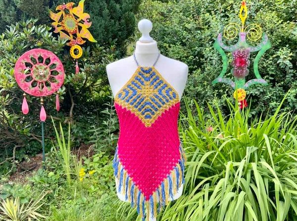 Gehäkeltes Neckholder-Top in Pink, Blau und Gelb mit Fransen an Schaufensterpuppe vor Garten