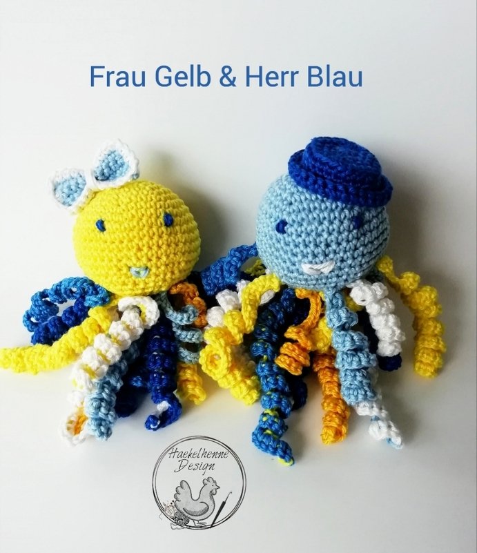 Zwei gehäkelte Amigurumi-Oktopusse, gelb mit Schleife und blau mit Hut, mit bunten geringelten Tentakeln