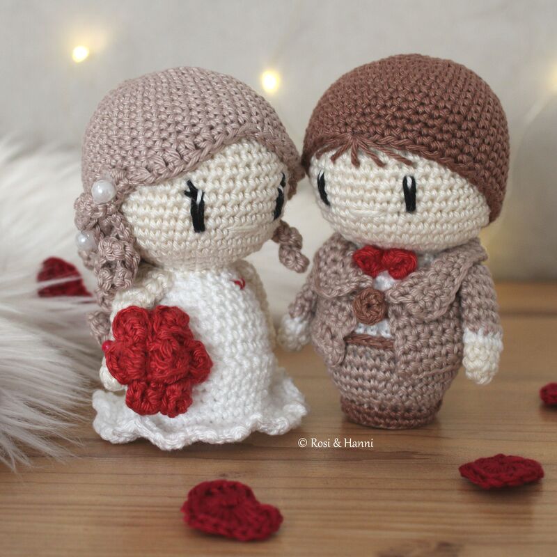 Gehäkeltes Amigurumi-Brautpaar mit rotem Strauß und braunem Anzug auf Holzuntergrund