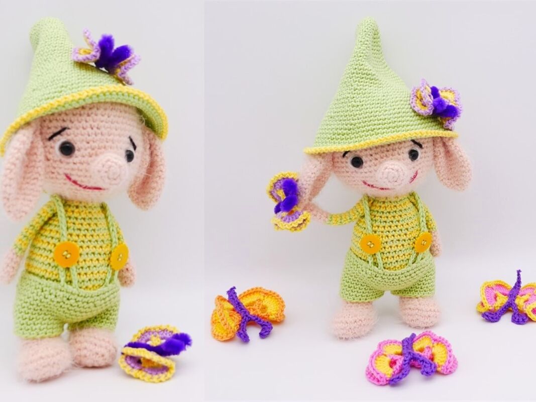 Pastellgrüne Amigurumi-Figur mit gelben Knöpfen und Häkelblüten