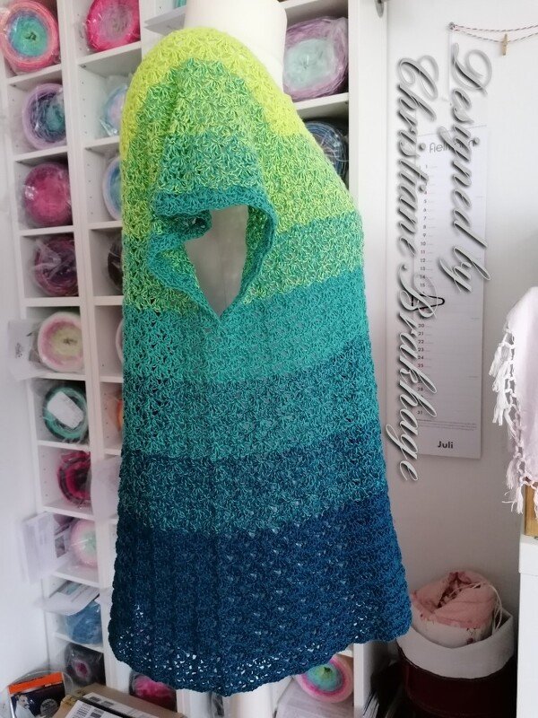 Mannequin trägt gehäkelte Tunika mit Kurzarm in Farbverlauf von Gelbgrün über Türkis bis Dunkelblau