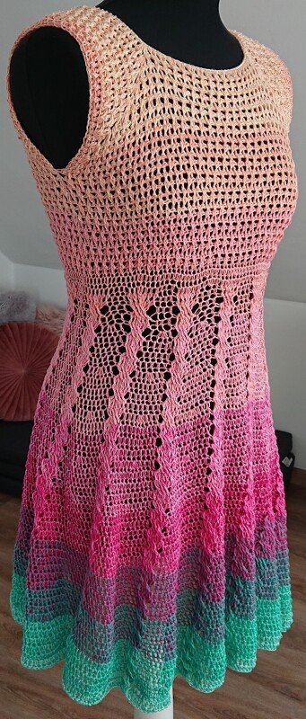 Ärmelloses gehäkeltes Damenkleid in Ombré‑Farben (Rosa bis Türkis) auf Schneiderpuppe.
