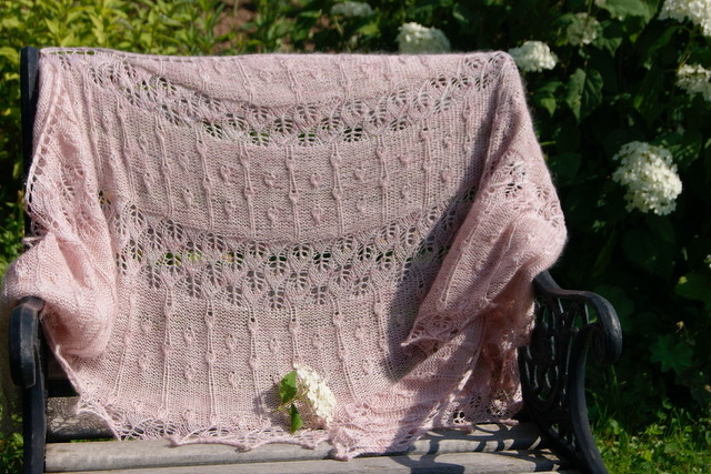 Rosafarbenes Lacetuch mit Lochmuster auf dunkler Gartenbank