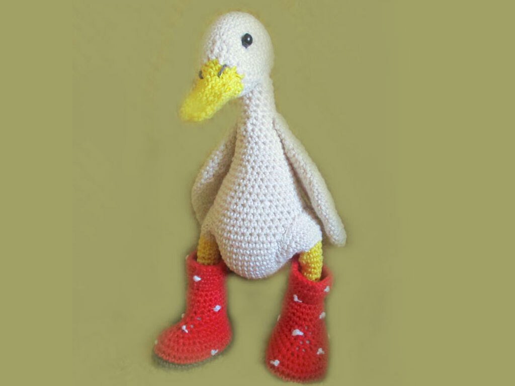 Close-up of crocheted duck showing body texture, yellow beak and red crochet boots