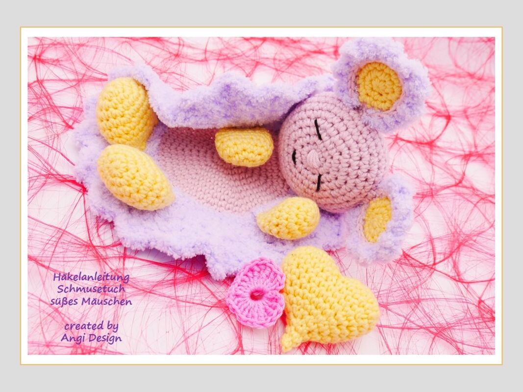 Gehäkeltes Schmusetuch in Lila und Gelb mit Mäusekopf, Herz und Blüte auf rosa Untergrund.