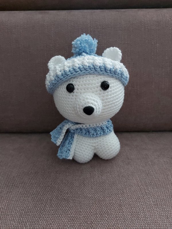 Weißer gehäkelter Amigurumi-Eisbär mit blauer Mütze und Schal