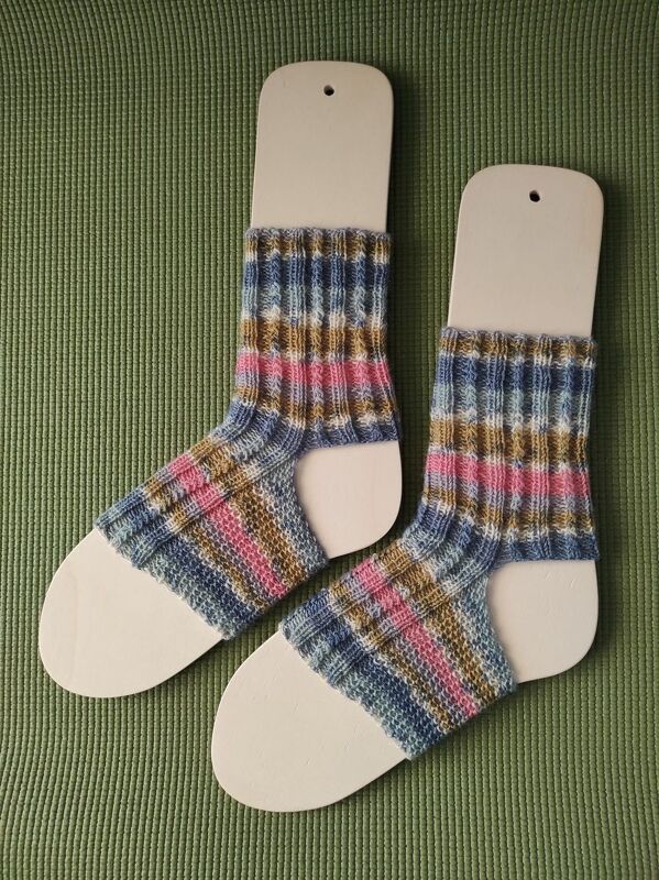 Paar gestrickter Damensocken mit Rippenbündchen und bunten Streifen auf Holz-Sockenspannern