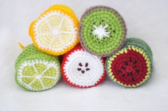 Close-up of small round crochet fruit motifs stacked in two rows