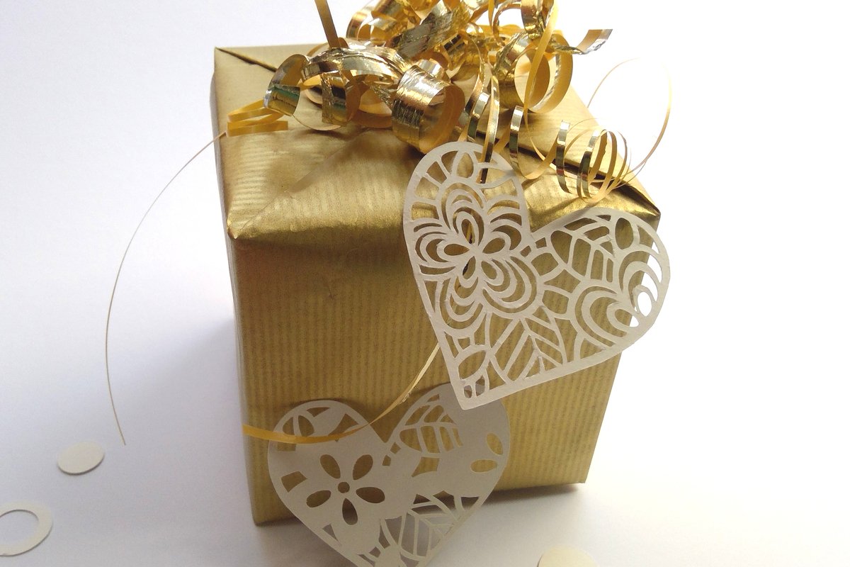 Goldenes Geschenk mit zwei geplotteten Herzanhängern aus Papier und goldenen Bändern
