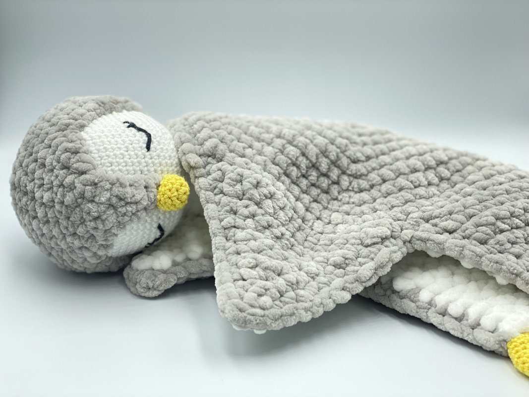 Grey crocheted penguin lovey with plush head and textured blanket