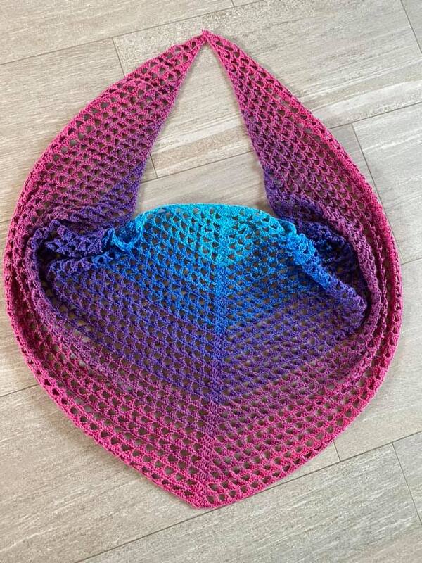 Gehäkeltes Dreieckstuch mit Farbverlauf von Pink über Lila zu Blau auf hellem Holzboden