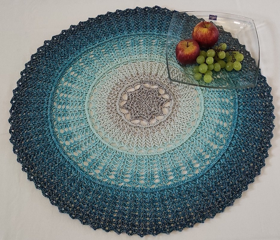 Rundes gehäkeltes Deckchen in Blau‑Grau mit Glasschale und Obst
