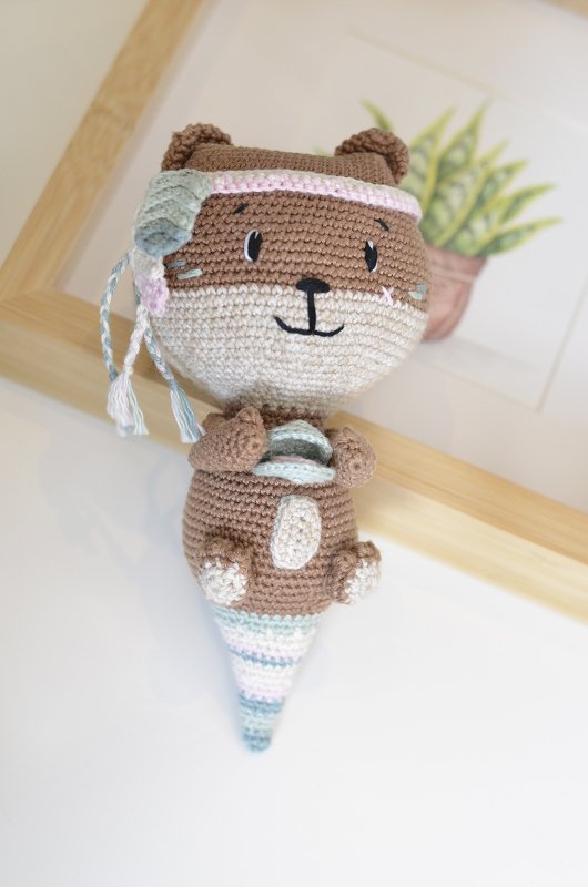 Gehäkeltes Seeotter‑Amigurumi in Braun und Pastelltönen, hält eine Muschel