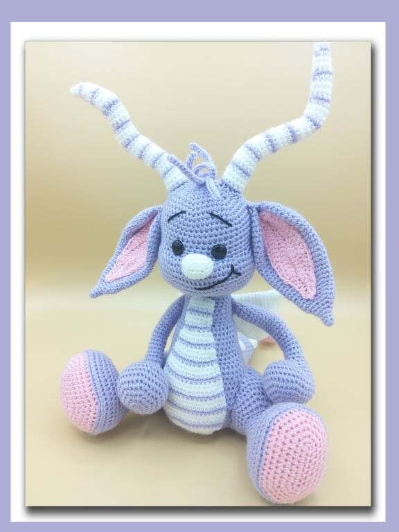 Lavendelfarbener gehäkelter Amigurumi-Drache mit rosa Akzenten und gestreiften Hörnern