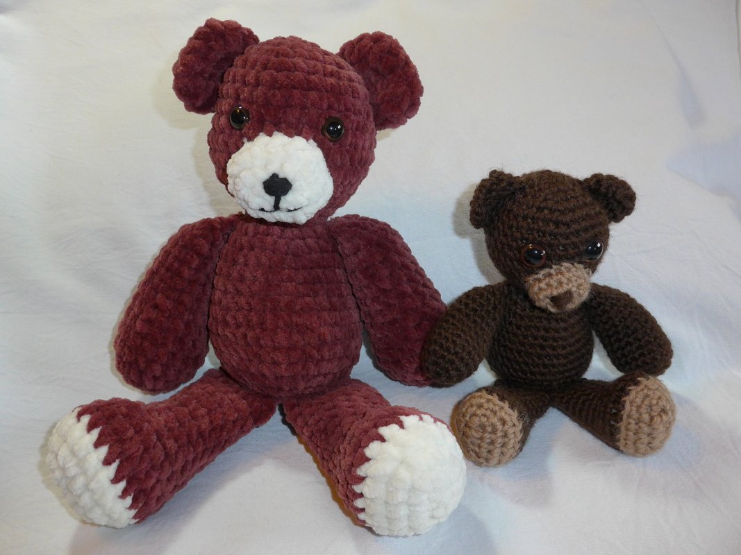 Zwei gehäkelte Amigurumi-Teddybären: großer weinroter Bär mit weißer Schnauze und Pfoten, kleiner dunkelbrauner Bär mit beigen Details.