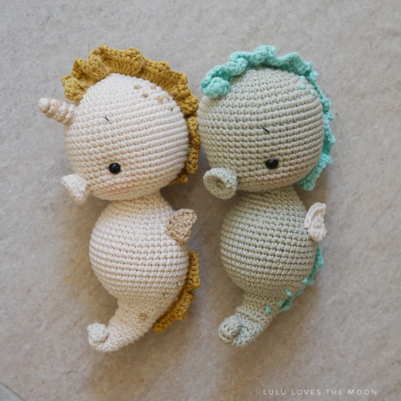 Pair of crocheted seahorse amigurumi in cream and sage with ruffled manes
