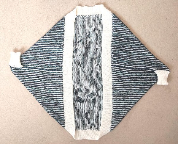 Offener gestrickter Seelenwärmer, blau-weiß gestreift, mit breiter cremefarbener Frontblende, flach ausgelegt.