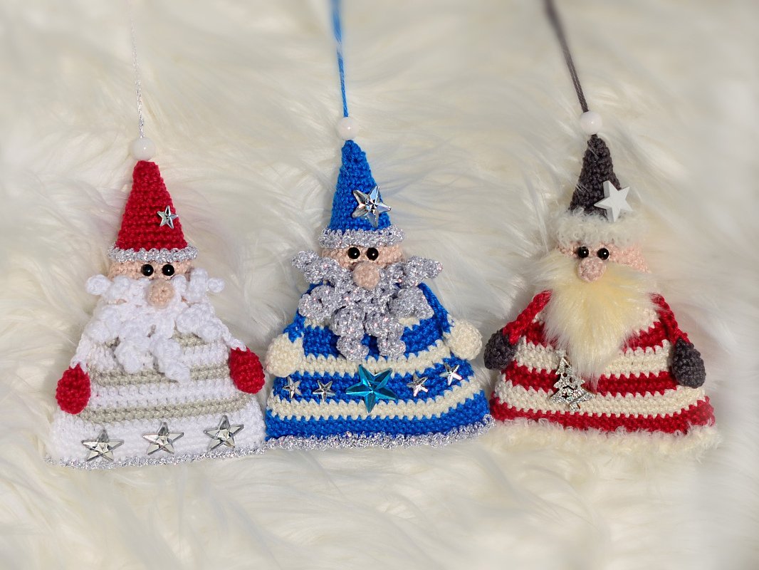 Drei gehäkelte Wichtel-Anhänger in Rot, Blau und Grau mit unterschiedlichen Verzierungen
