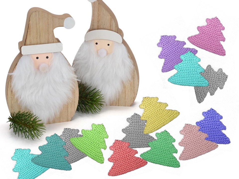 Zwei dekorative Holz-Wichtel mit weißen Bärten neben mehreren gehäkelten Tannenbaum-Applikationen in Pastellfarben und Tannenzweigen.