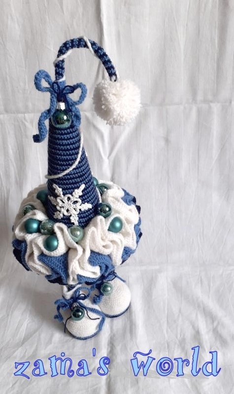 Gehäkelte blau-weiße Weihnachtsdekoration mit kegelförmigem Aufsatz, Bommel, Schneeflocke, Kugeln und kleinen Babyschuhen.