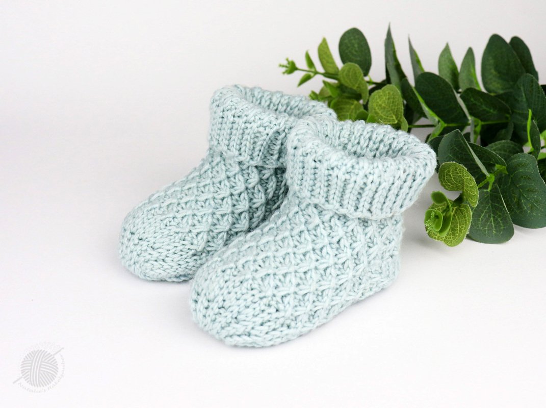 Pair of pale mint crocheted baby booties with textured stitch and fold-over ribbed cuffs