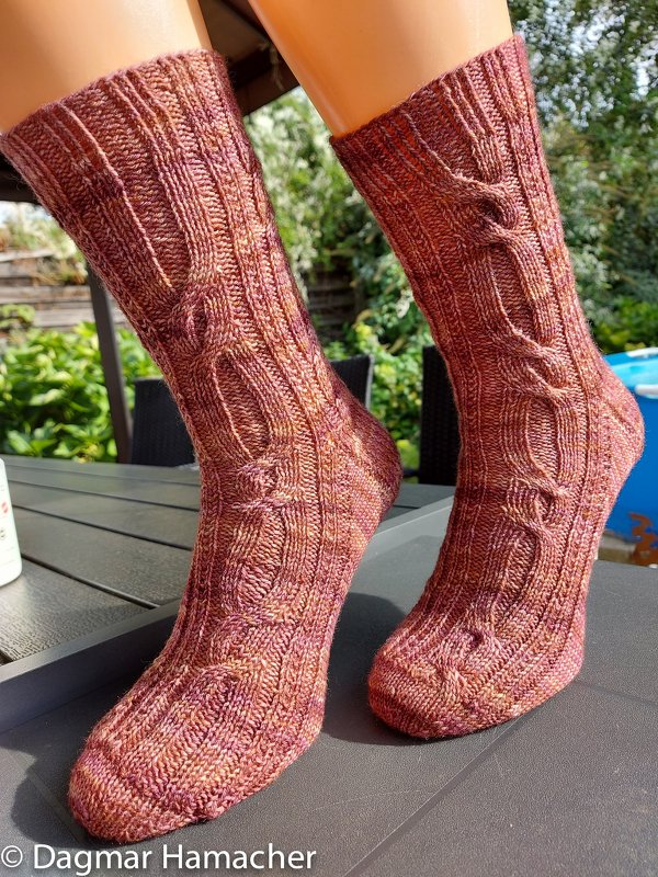 Wadenlange gestrickte Damensocken in rotbraunen Meliertönen mit Zopfmuster auf Sockenform