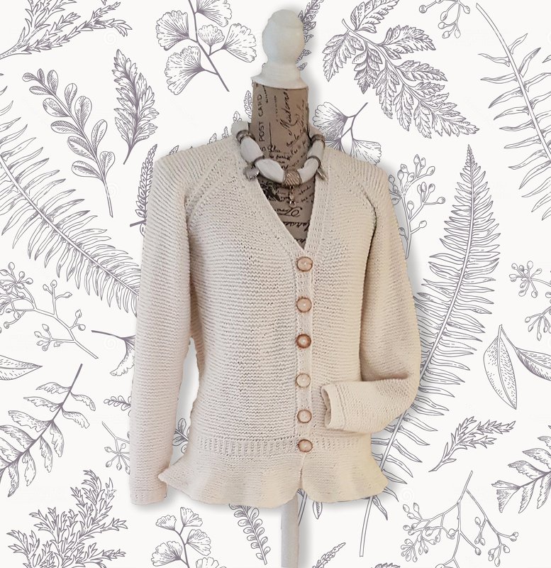Cream knitted V-neck cardigan with raglan-style sleeves, six brown buttons and a ruffled hem on a mannequin.