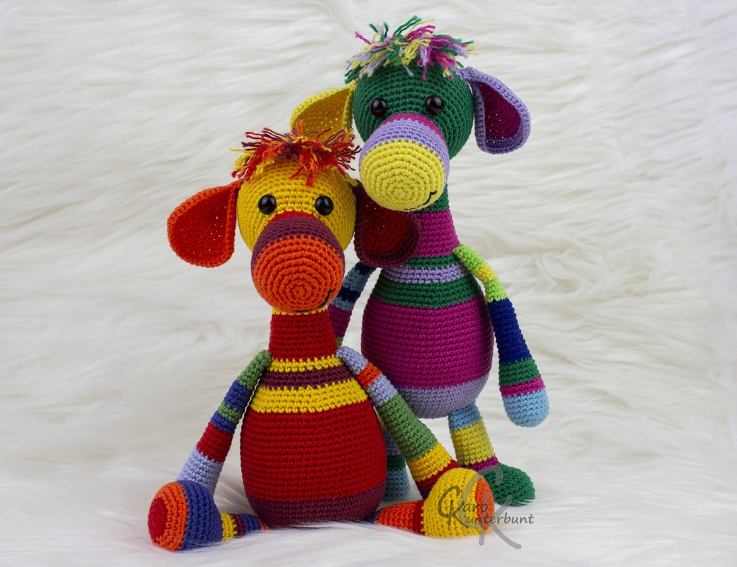 Zwei gehäkelte, gestreifte Amigurumi-Figuren in bunten Farben auf weißem Hintergrund