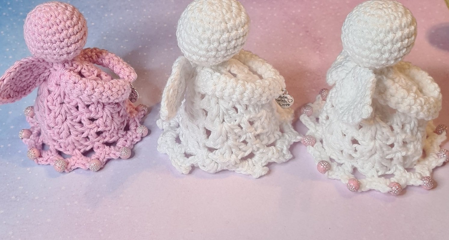 Drei gehäkelte Engel in Rosa und Weiß mit Spitzenrock und Perlenrand
