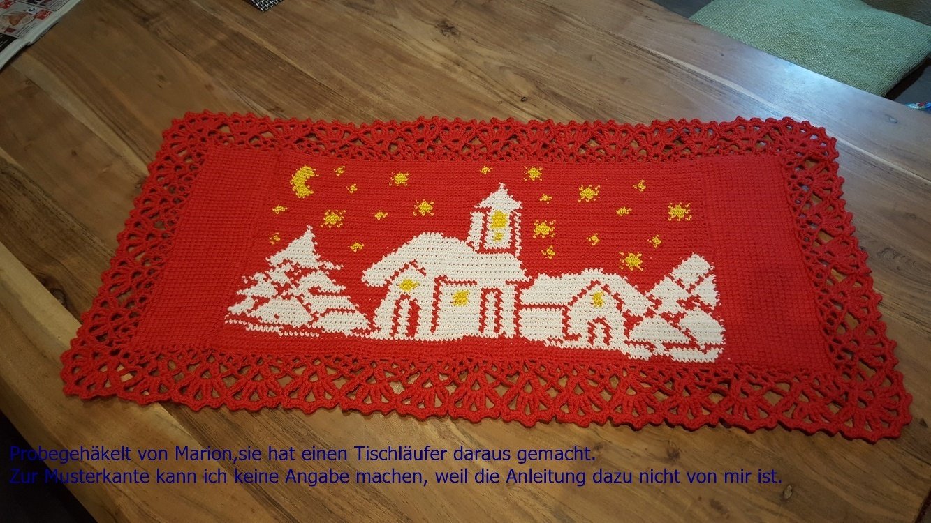Roter gehäkelter Tischläufer mit weißem Winterdorf-Motiv und gelben Akzenten